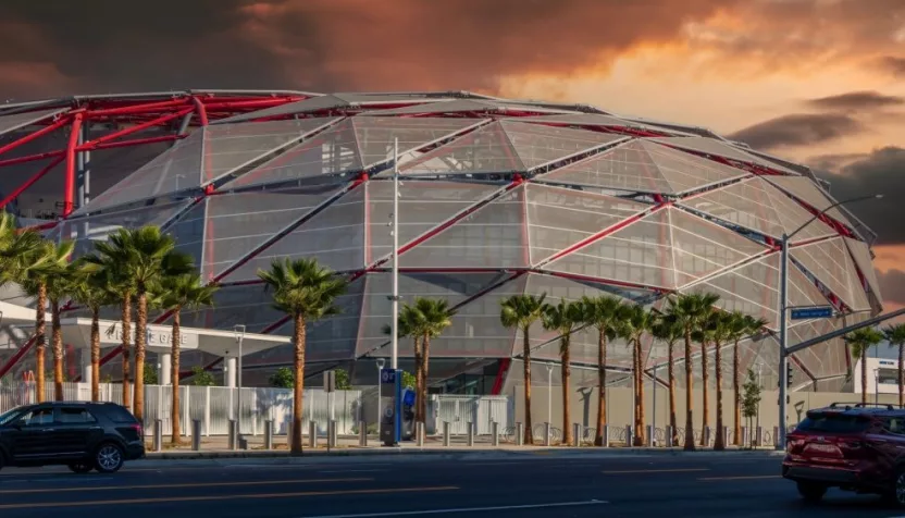 The Intuit Dome with cars driving on the street^ lush green palm trees and powerful clouds at sunset in Inglewood California USA. Inglewood^ California USA - 10 22 2024