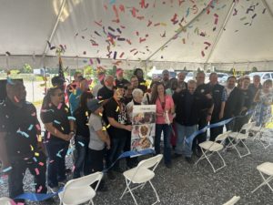 Group of people lined up, cutting ribbon, confetti in the air