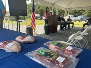 Slabs of meat on a table with speaker standing at lectern in the background.
