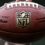 NFL professional athlete holds a ball for American football.