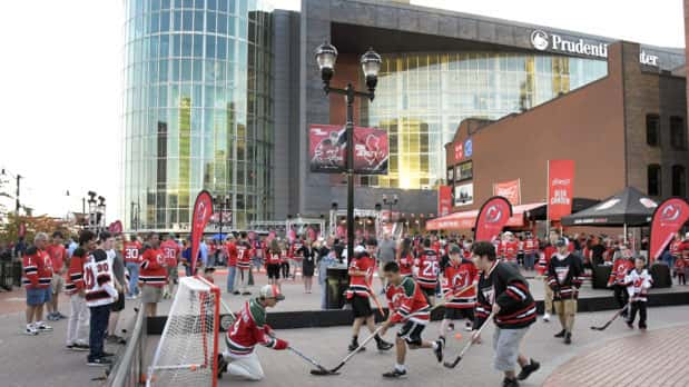 Fans play street hockey outside the Prudential Center before the New Jersey Devils' NHL hockey home-opener against the Anaheim Ducks, Tuesday, Oct. 18, 2016, in Newark, N.J. (AP Photo/Bill Kostroun)