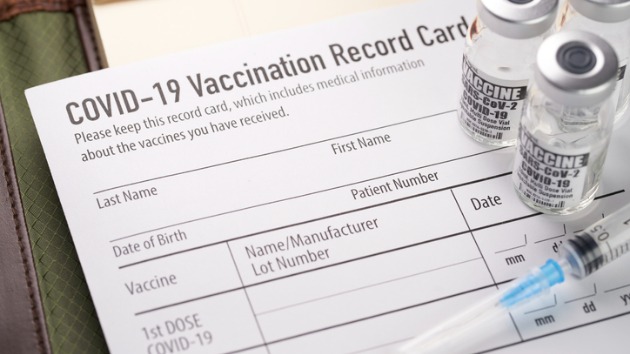 covid19-vaccination-record-card-with-vials-and-syringe-picture-id1289454645