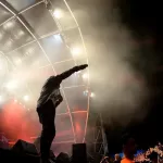 rapper/artists performing on stage^ holding mic to the crowd^ silhouette/lighting in white and red