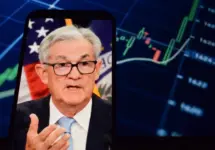 On the smartphone screen^ Federal Reserve (Fed) Chair Jerome Powell is visible. In the background^ an inflation rate chart is displayed. 19.04.2025. New York^ U.S