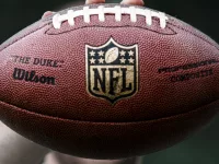 NFL professional athlete holds a ball for American football.