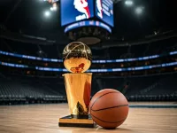 Indoor photo of photography of a basketball and next to it the larry o’brien nba championship trophy lying on a basketball court in an nba arena