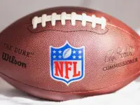 NFL Wilson Duke ball over a white sofa in a home. Sun light comes from a window.