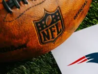 New England Patriots NFL team Logo and American football ball on Green Grass.