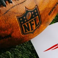 New England Patriots NFL team Logo and American football ball on Green Grass.