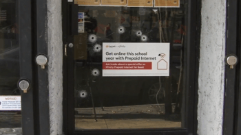 bullet holes in glass door of cell phone store in philly